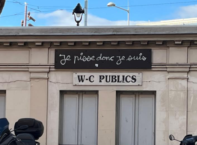 image shows French public bathroom with "I pee therefore I am" written above it in French